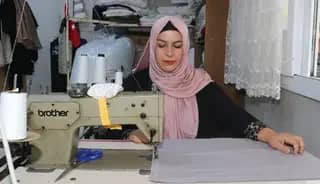 Kadın muhtar mahallelinin hem derdini dinliyor hem terziliğini yapıyor