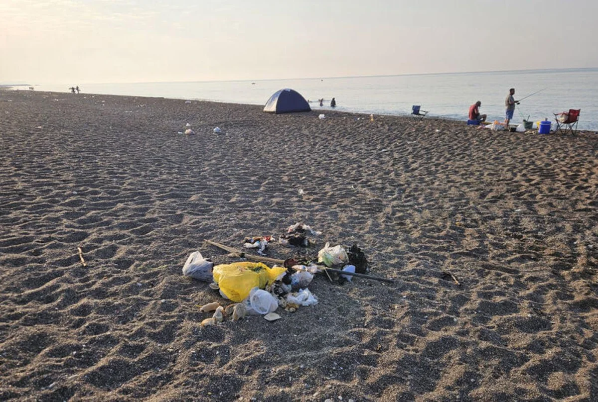 Kıyıda oturanların ve balık tutanların yakınında, plastik ve cam şişelerle dolu çöp yığınları bulunuyor. Deniz kıyısına yakın bölümlerde de poşetler, yiyecek ambalajları ve tek kullanımlık kaplar görülüyor.